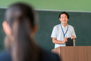 教室の黒板の前で授業をする男性教師
