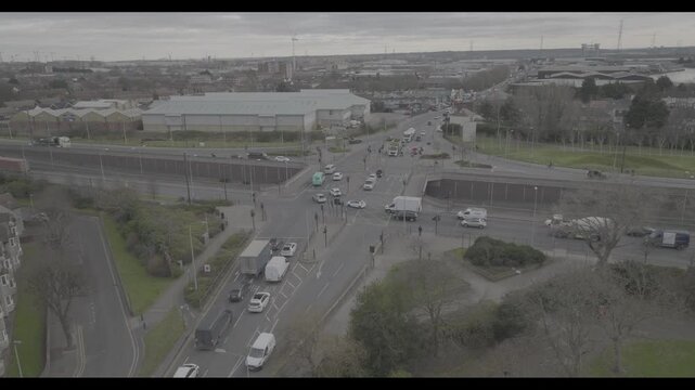 Vehicles passing crossroad in suburbs on cloudy day. Aerial static shot of traffic in town. London, UK