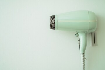 Pale green hair dryer mounted on a wall.
