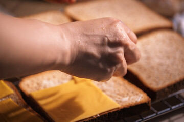 Hand placing cheese on bread
