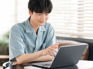 若い日本人男性がノートパソコンを開き作業をしている。