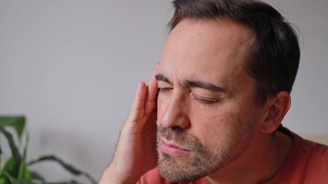 Close up Man touching temple, forehead and head due to headache and feeling unwell