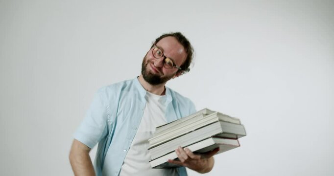 A man flexes his muscles while holding a stack of books, showcasing his strength and love for reading. He smiles at the camera, exuding confidence and pride in his literary pursuits.