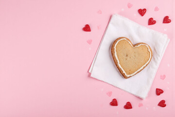 heart shaped cookie on a pink background surrounded by red hearts