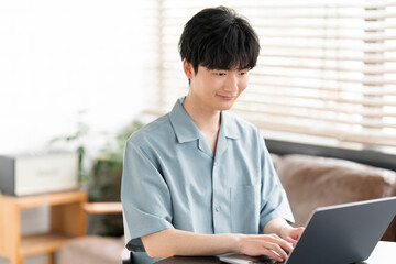 若い日本人男性がノートパソコンを開き作業をしている。