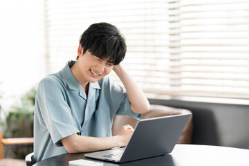 若い日本人男性がノートパソコン開き作業をしている。