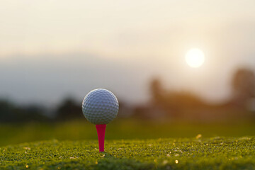 Close-up golf ball on tee with blur green bokeh background.