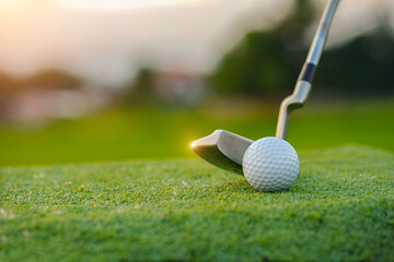 Golf clubs and golf balls on a green lawn in a beautiful golf course with morning sunshine.