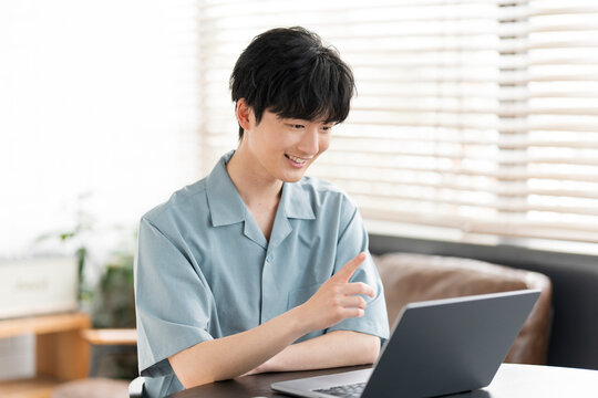 若い日本人男性がノートパソコンを開き、オンラインミーティングをしている。