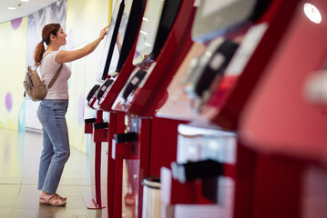 Caucasian woman buying cinema ticket at self-service box office.