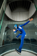 A man in overalls and a protective helmet enjoys flying in a wind tunnel. Free fall simulator