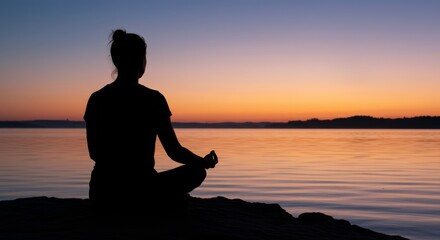 Silhouette of woman meditating by the water at sunset for wellness