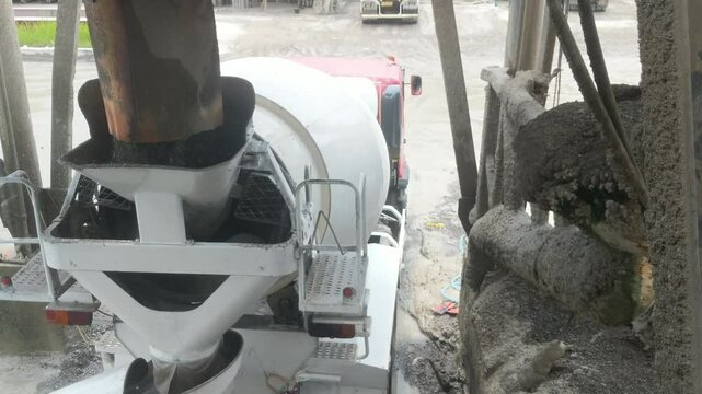 concrete mixer truck loading concrete mortar, A top-down view shows a concrete mixer truck actively discharging wet concrete at a construction site, surrounded by heavy machinery