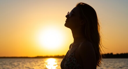Silhouette of a woman in sunglasses enjoying a serene sunset by the sea
