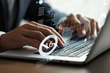 Focused professional working on laptop with digital interface and data analysis in background...