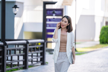 A woman is talking on her cell phone while walking down a sidewalk