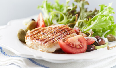 Grilled Turkey Breast with fresh salad. Bright background.	