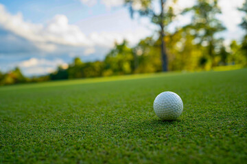Golf ball is on a green lawn in a beautiful golf course with morning sunshine.