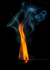 Dramatic image of an ignited matchstick emitting vibrant orange flames with delicate blue smoke...