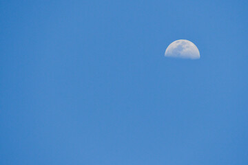 a beautiful half moon against a blue sky