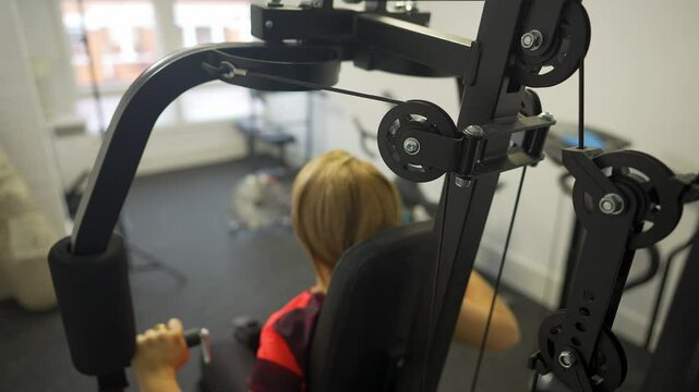 Woman on her back doing bodybuilding exercises on a gym machine at home.
