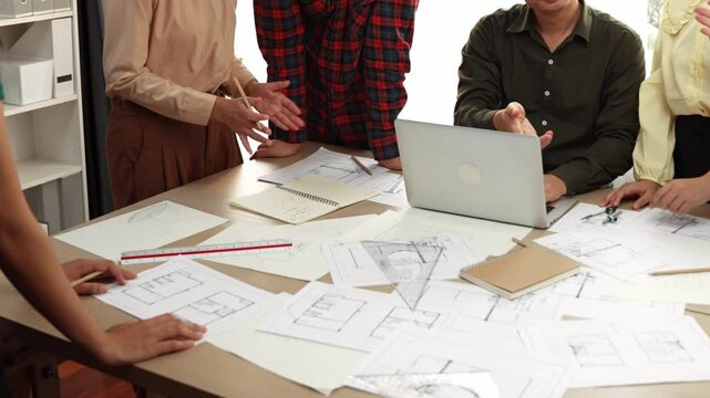 Architect and safety engineer celebrate success design building blueprint project on laptop on table with architectural document and wooden block scatter around at modern office. Closeup. Delineation.