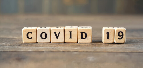 Wooden cubes spelling Covid 19, focus concept on a wooden background. Pandemic, virus, health, information and communication related concepts. Conceptual representation.