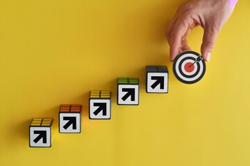 Goal Achievement Concept Hand Placing Target on Arrow Blocks on Yellow Background in Studio