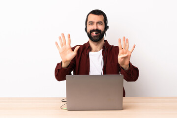 Telemarketer caucasian man working with a headset and with laptop counting nine with fingers.