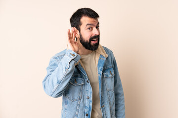 Caucasian man with beard over isolated background listening to something by putting hand on the ear