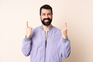 Caucasian man with beard wearing a jacket over isolated background pointing up a great idea