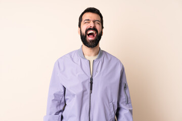 Caucasian man with beard wearing a jacket over isolated background shouting to the front with mouth wide open