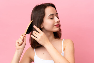 Young Ukrainian woman isolated on pink background with hair comb