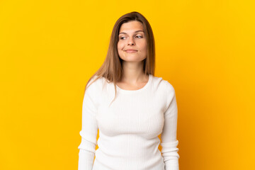 Young Slovak woman isolated on yellow background having doubts while looking side