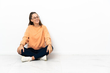 Fototapeta premium Young woman sitting on the floor looking to the side and smiling