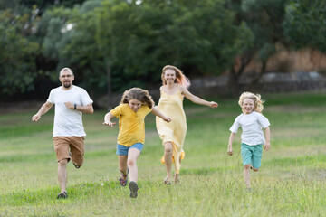 Fototapeta premium Happy family running and playing together in a park