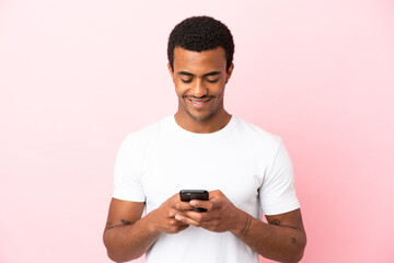 African American handsome man on isolated pink background sending a message or email with the mobile