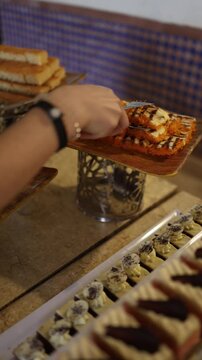 Vertical screen rich orange knafeh layered with cream and drizzled with syrup sits on an ornate tray beside soft basbousa and elegant mousse cakes in a warm oriental dessert spread