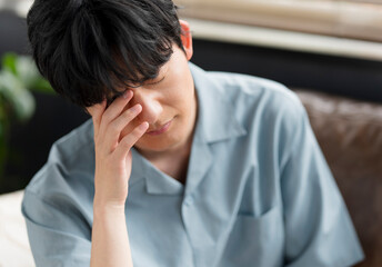 体の不調を感じている若い日本人男性。