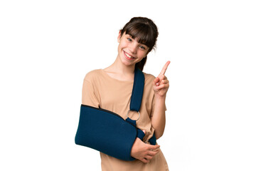 Little caucasian girl with broken arm and wearing a sling over isolated background showing and...