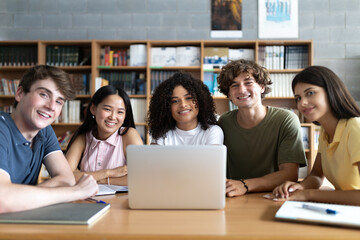 Happy students smiling in library with laptop for group project