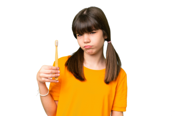 Little caucasian girl brushing teeth over isolated background with sad expression