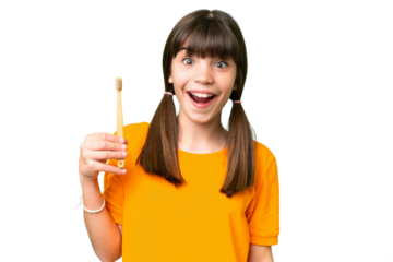 Little caucasian girl brushing teeth over isolated background with surprise and shocked facial expression