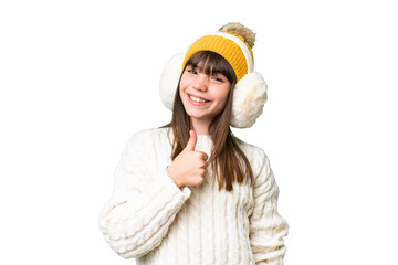 Little caucasian girl wearing winter muffs over isolated background giving a thumbs up gesture