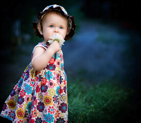 Adorable toddler girl in a colorful floral dress and hat holding a daisy. Outdoor portrait with soft lighting, capturing innocence and childhood charm, ideal for childhood advertising