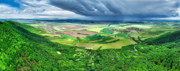 Storm rainy clouds above a village and green mountain and field landscape - panorama of Slovakia