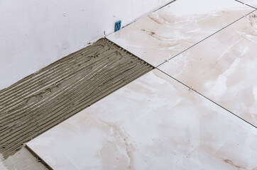 Przyklejanie płytek podłogowych z bliska, duże ceramiczne plytki