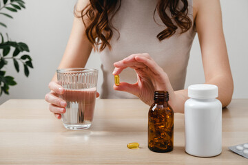 A woman holds omega-3 fish oil capsules. Healthy lifestyle, prevention and treatment of diseases. The woman takes and drinks dietary supplements and vitamins for skin, nails and hair. 