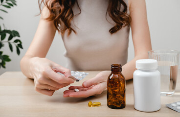 A woman holds omega-3 fish oil capsules. Healthy lifestyle, prevention and treatment of diseases. The woman takes and drinks dietary supplements and vitamins for skin, nails and hair. 