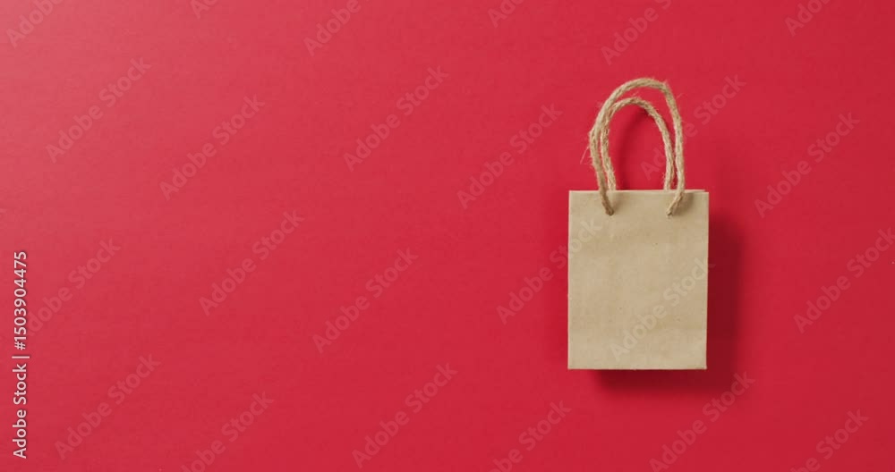 Poster small brown gift bag with string handles on red background with copy space